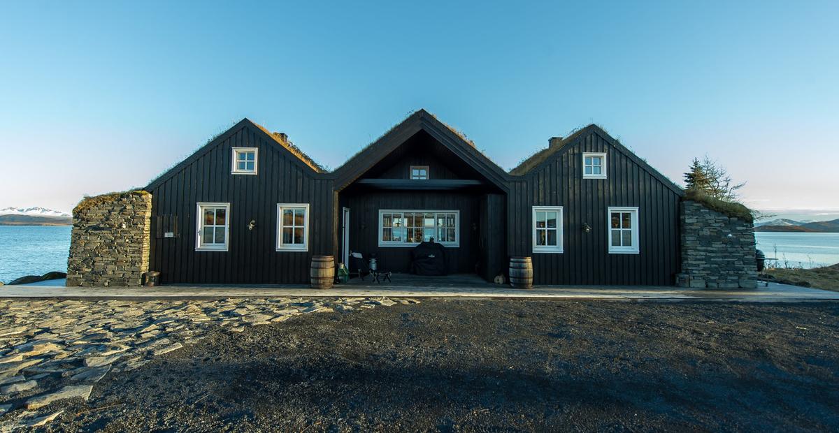 A close-up of the cabin facade, showing the black timber cladding and turf roof on this Thingvellir Lake cottage