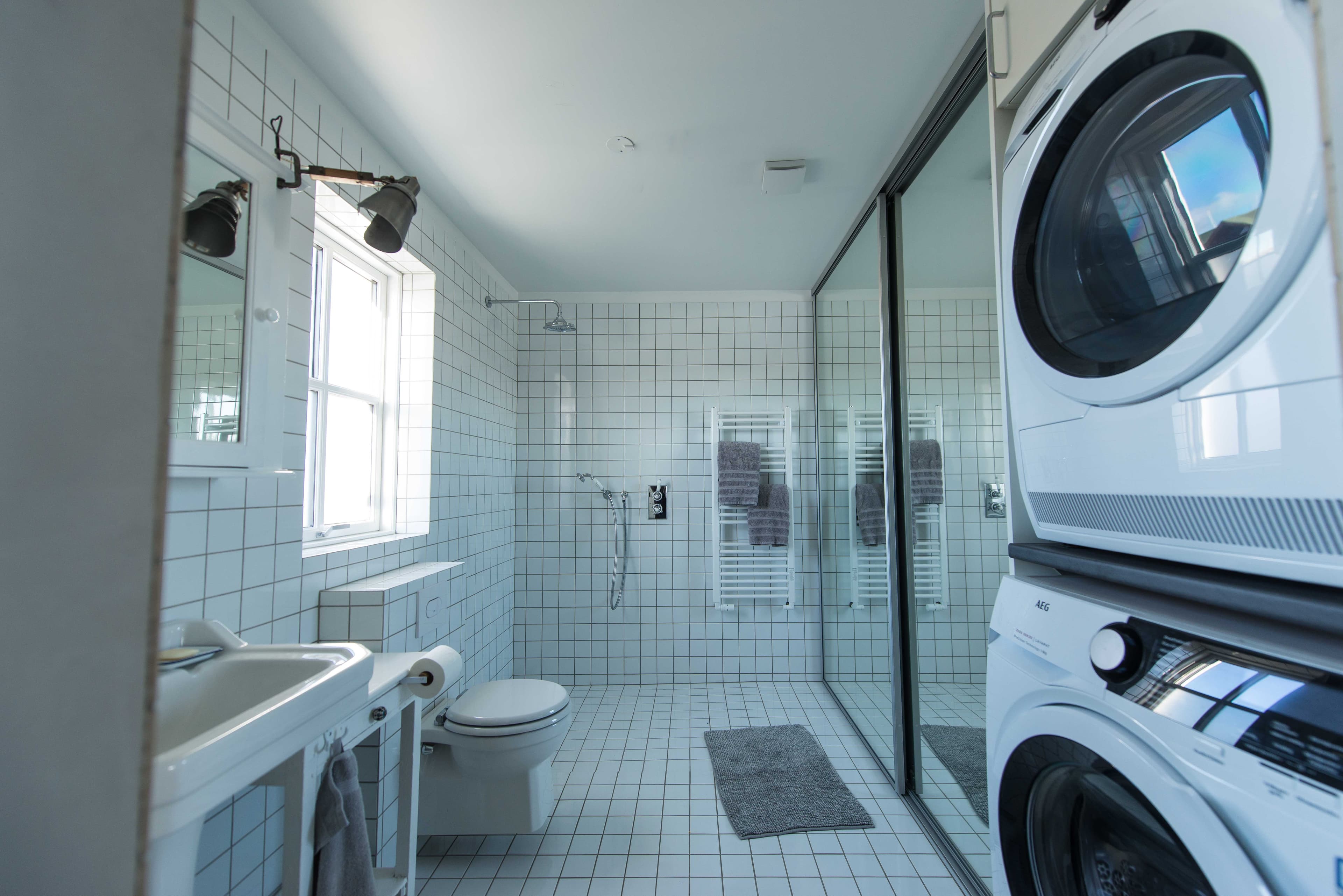 Modern bathroom with a walk-in shower and washing machine, dryer